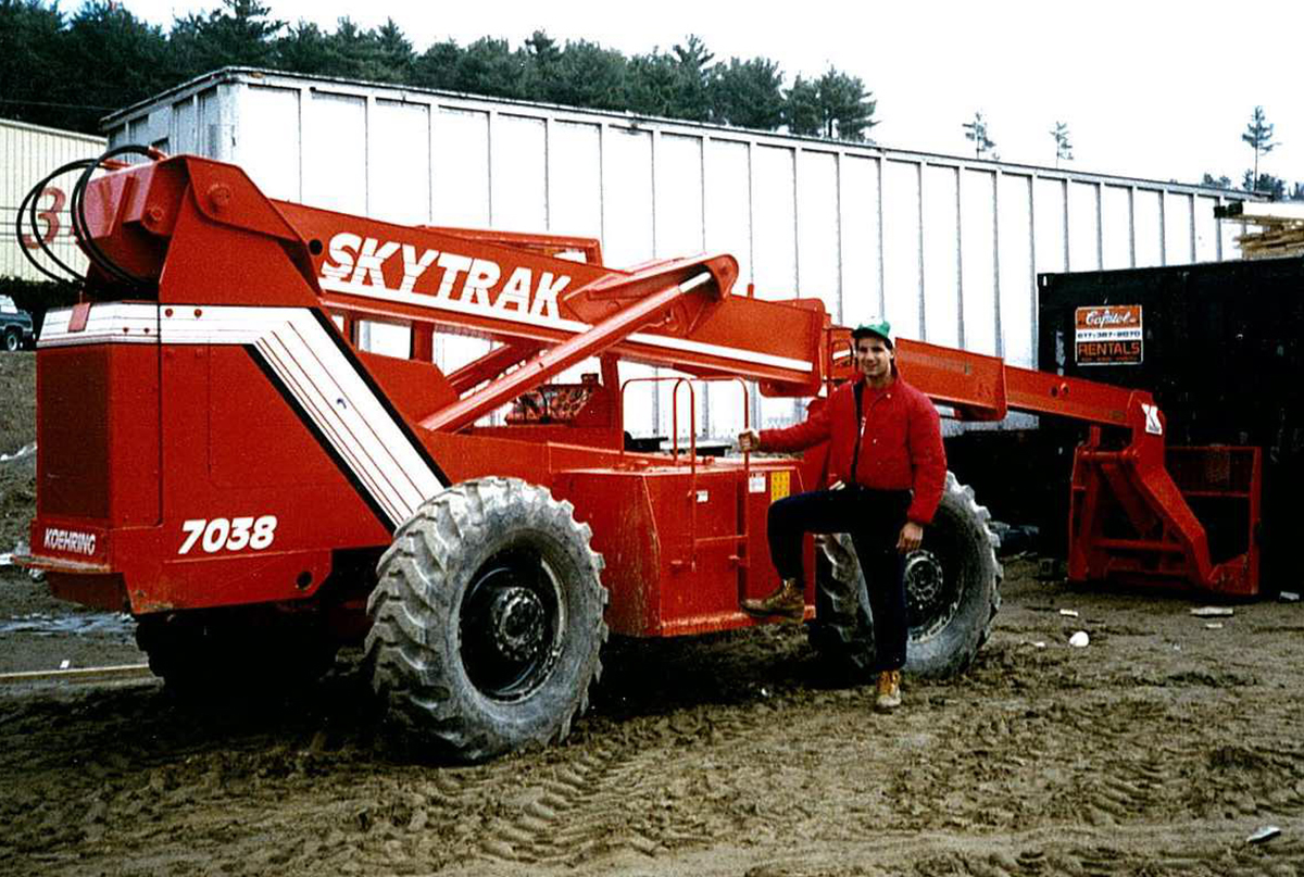John Wise stands next to a bright red front loader sometime in the late 90s.